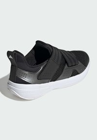 Chaussure de sport noire avec une tige en mesh, une semelle en caoutchouc et des sangles en velcro. Présente des accents brillants et des détails perforés sur les côtés.