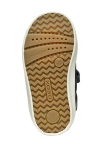Suela de zapatilla negra con un patrón en zigzag, con perforaciones para la transpirabilidad, etiquetada con "GEOX", "SISTEMA FLEXI" y "SUAVEMENTE AMORTIGUADA."