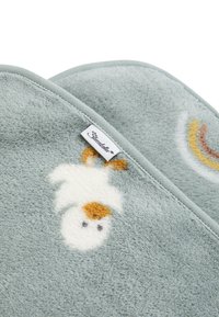 Soft, light blue blanket featuring a white cloud and rainbow design, with an embroidered duck motif and a tag edge. Plush texture.