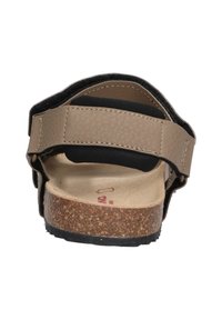 Bruine sandaal met verstelbare zwarte band, kurken voetbed en textuur synthetisch bovenwerk. Achteraanzicht toont de zachte binnenvoering en rubberen zool.