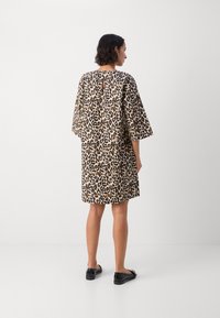 Haljina s uzorkom leoparda izrađena je od laganog materijala, s opuštenim krojem, širokim rukavima i detaljem u obliku otvora na leđima. Nosiva s crnim balerinkama.