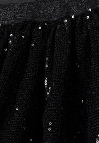 Zwarte paillettent stof met een getextureerd breipatroon, voorzien van een geplooid ontwerp en een gladde tailleband aan de bovenkant.