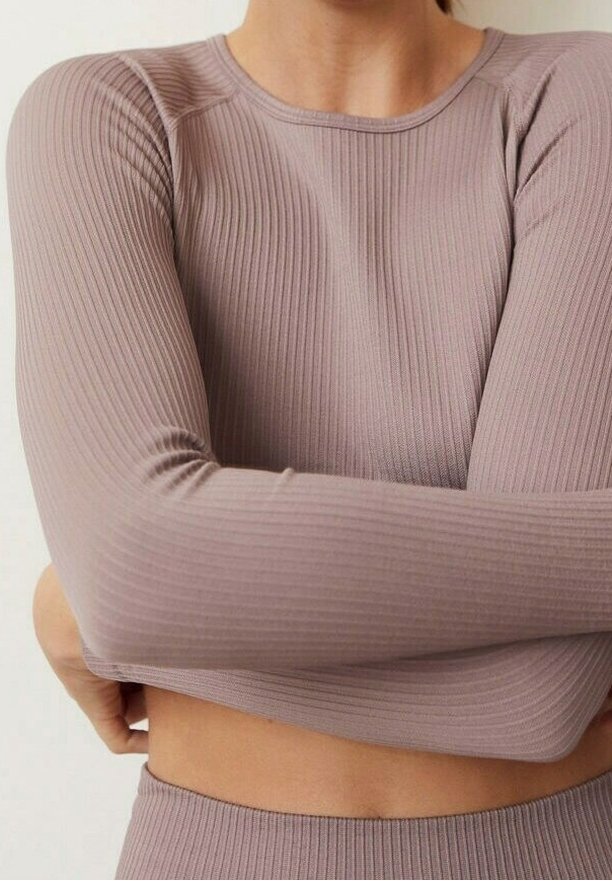 Dopasowany top z długim rękawem w kolorze stonowanego fioletowego, z prążkowanego materiału, miękka tekstura, okrągły dekolt i bezszwowe ramiona zwiększające swobodę ruchów.