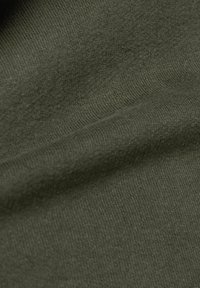 Nahaufnahme von olivgrünem gestricktem Stoff, der die detailreiche Textur und das Muster der Maschen zeigt.