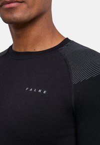 T-shirt de sport noir avec logo FALKE, doté d'un tissu texturé, d'un col côtelé et d'accents rayés sur les épaules.