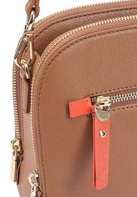 Bruin leren schoudertas met gouden hardware, dubbele ritsen en een oranje accentlip. Textuur oppervlak met stiksel details.