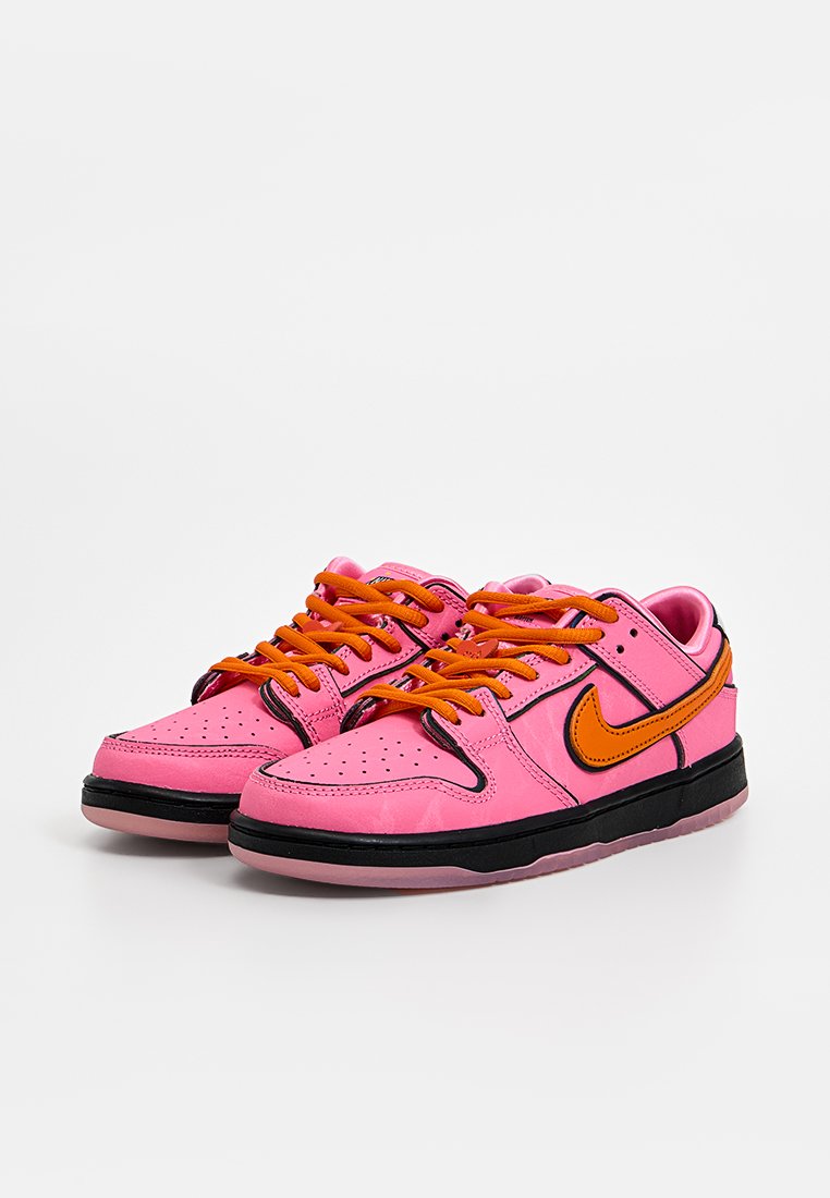 Baskets en cuir rose avec des lacets orange et le logo Nike, accents noirs, dessus texturé et boîte de toe perforée, avec une semelle translucide.