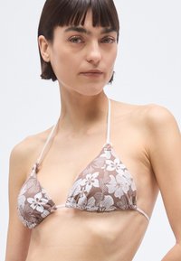 Hnedý trojuholníkový vrchný diel bikin s kvetinovým vzorom, bielymi detailmi, nastaviteľnými ramienkami, zhrnutou látkou a malým logom na boku.