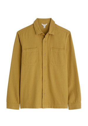 Camisa de manga larga en tela amarilla mostaza con un acabado texturizado, que cuenta con un cuello clásico, dos bolsillos frontales en el pecho y cierre de botones.
