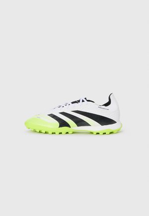 White soccer shoe with black accents, featuring a textured upper and bright yellow-green sole. Designed for grip on turf surfaces.