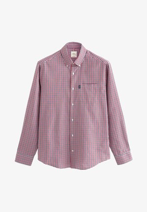 Piros és kék kockás, hosszú ujjú ing, gombos gallérral, egyetlen mellzsebbel, valamint gombos záródású elülső részekkel és mandzsettákkal.