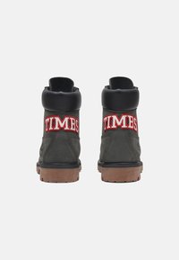 Botas de cuero verde oscuro que cuentan con un cuello acolchado negro y bordado rojo "TIMBS" en la parte trasera. Suela de goma con agarre texturizado.