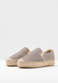 Licht bronzen instap espadrilles met een geweven textiel bovenwerk, een natuurlijke jute zool en gestikte details langs de middenzool.