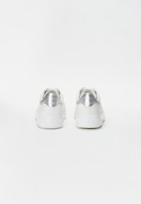 Białe sneakersy z srebrnymi akcentami, górą z gładkiej skóry i podwyższoną, teksturowaną podeszwą. Zaokrąglony czubek i wyściełany kołnierz dla komfortu.