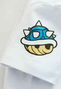 Valge puuvillane T-särk, millel on varrukal sinise okaste ja pruunide nägudega kestaga graafika. Sile tekstuur ja mugav lõige.