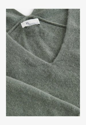 Zeleni volneni pulover z globokim V-izrezom, ki se ponaša s prijetno mehko teksturo in oznako "N. PREMIUM COLLECTION." Pod kotom prikazana podrobnost o ovratniku.