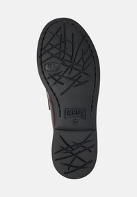 Zwarte rubberen schoenzool met een getextureerd loopvlak voor grip, met 'CAMPPER' merk en maatmarkering '38'. Gladde randen, minimalistisch design.