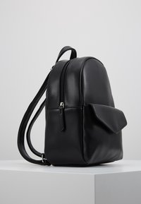 Černý kožený batoh s oblejším designem, se zipem na vrchu a přední kapsou s klopou. Texturovaný povrch a dvojité ramenní popruhy.