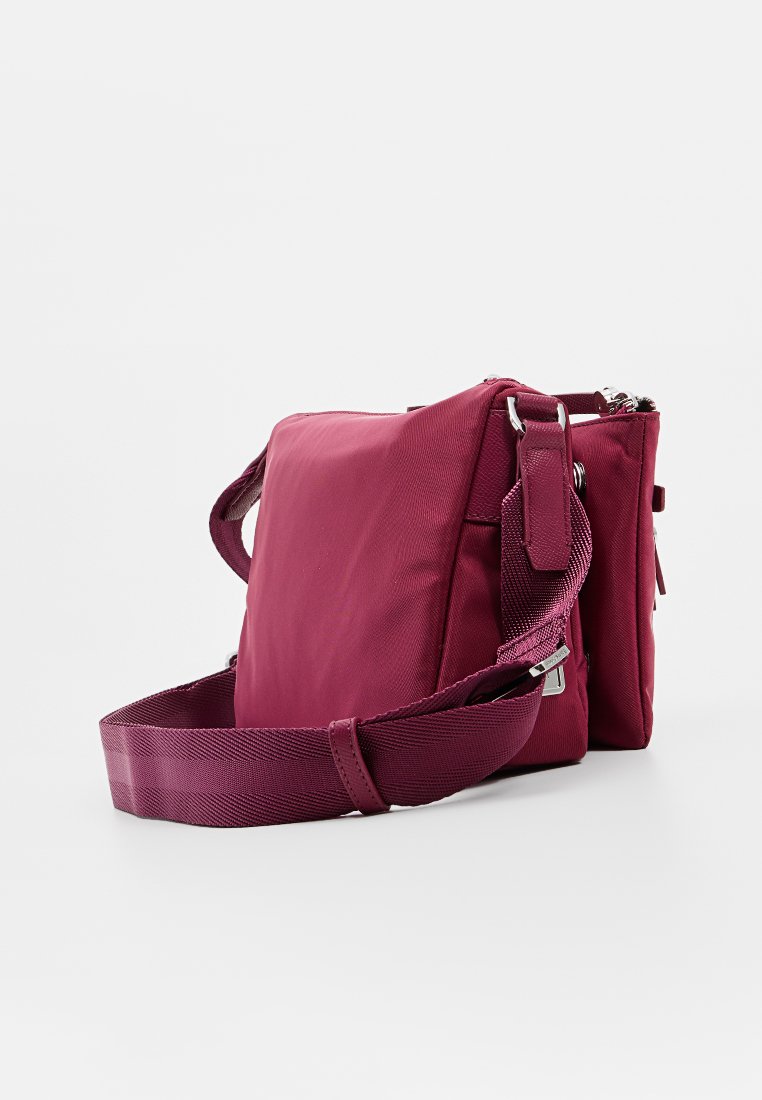 Bolso cruzado de nailon carmesí con una textura suave, correa ajustable, cierre de cremallera y acentos de hardware en plateado. Forma rectangular compacta.