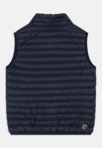 Námořnická modrá prošívaná vesta bez rukávů s vysokým límcem a kruhovou nášivkou loga nedaleko spodního lemu na zadní straně.