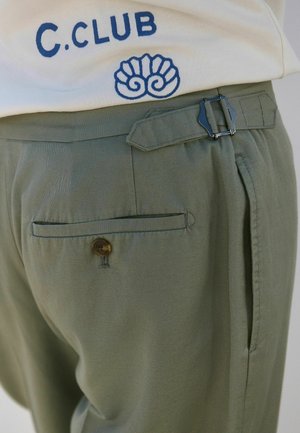 Olive green pants featuring a buttoned back pocket, belt loops, and a metal buckle detail at the waist. Smooth, textured fabric.