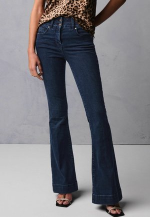 Tmavě modré rozšířené džínsy s vysokým pasem a čtyřmi knoflíky. Materiál vypadá jako denim se hladkou texturou a minimálními švy.