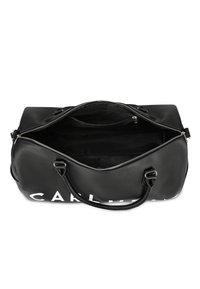 Černá sportovní taška vyrobená z texturované kůže, s zipovým uzávěrem, dvojitými uchy a bílým logem na boku. Uvnitř je prostorná a podšitá.