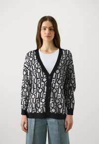 Cardigan lavorato a maglia con un motivo geometrico bianco e nero, maniche lunghe, scollatura a V profonda e bottoni frontali. Polsini e orlo a coste.