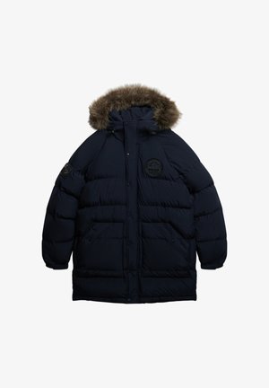 Puchowy granatowy płaszcz z kapturem wykończonym futrem, zamkiem błyskawicznym i zapięciem na napy, dwoma przednimi kieszeniami oraz okrągłym haftowanym logo na piersi.