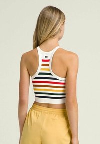 Top corto de canalé en blanco con rayas horizontales multicolores. Presenta un diseño de espalda nadadora y un pequeño logo en la parte posterior.