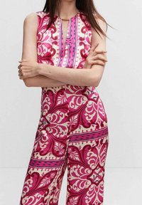 Combinaison à motif rose et crème avec un design sans manches, présentant un décolleté en forme de clé et de grands motifs floraux et accents.