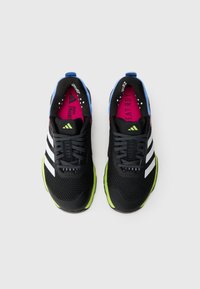 Black athletic shoes with mesh upper, white stripes, and a green outsole. Features colorful accents in blue and pink on the tongue and insole.