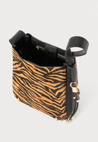 Sac en cuir noir avec motif tigre en peau de mouton, fermeture zippée en haut, bandoulière amovible et accents en métal.