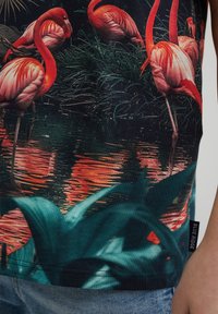 Kortärmad skjorta med ett livligt flamingotryck mot en mörk bakgrund, med gröna bladverk och en mjuk, slät tygtextur.