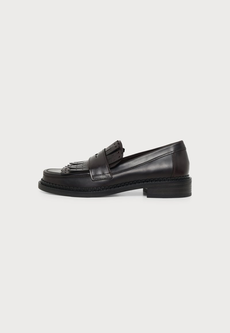 Mocassin en cuir noir avec détail de languette à franges et petit talon empilé, présenté de profil sur un fond clair uni.