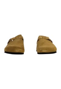 Chaussures en suède marron à enfiler avec un bout arrondi, dotées de deux sangles ajustables et d'une semelle plate en caoutchouc noir.