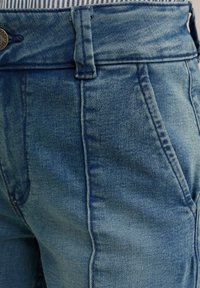 Jeans kratke hlače v svetlo modri barvi, z visokim pasom, sprednjimi žepi in teksturiranim pasom z deli in zaponko na gumb.