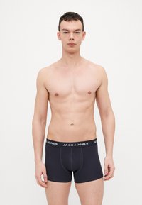 Sous-vêtements de style trunk noirs avec une coupe ajustée, une ceinture élastique portant la marque "JACK & JONES", présentant des détails de couture subtils et une texture lisse.