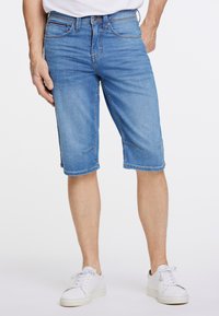 Jasnoniebieskie szorty cargo z denimu, o prostym kroju, do kolan, z przednimi kieszeniami i subtelnymi detalami szycia. W zestawie z białymi trampkami.