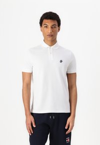 White polo shirt made from cotton, featuring a classic collar, two buttons, and a small black logo on the chest. Short sleeves.