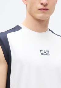 Top atlético sem mangas em branco com detalhes náuticos nos ombros. Apresenta um acabamento texturado e o logótipo EA7 na parte da frente.