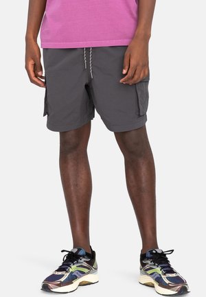 Shorts cargo gris avec poches latérales et taille à cordon, assortis à des baskets multicolores et un T-shirt violet.