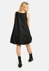 Fekete ujjatlan ruha laza szabással, sima anyagból készült. Kerek nyakkivágással és finom hátsó varrási részlettel rendelkezik.