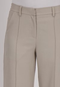 Beige broek met een rechte snit, uitgerust met een platte voorkant, riemlussen en zijnaad, gemaakt van een gladde stof met strakke lijnen.