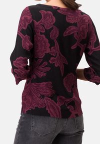 Suéter negro con un patrón floral texturizado en burdeos oscuro, con escote en forma de barco y mangas de tres cuartos.