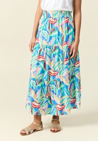 Gonna maxi di colore azzurro chiaro con motivi di foglie tropicali e fiori in rosso, rosa e verde. Presenta una vita elastica e un design a strati.