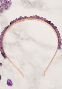 Opaska na głowę z kamieniem ametystowym z miedzianą podstawą, ozdobiona postrzępionymi fioletowymi kamieniami wzdłuż górnej krawędzi, na tle marmuru.