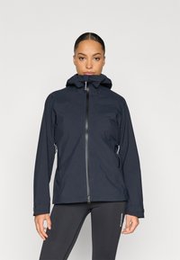 Tmavomodrá nepremokavá bunda s vysokým golierom, predným zipsom a nastaviteľnou kapucňou. Má bočné vrecká a elastické manžety pre pevné uchytenie.