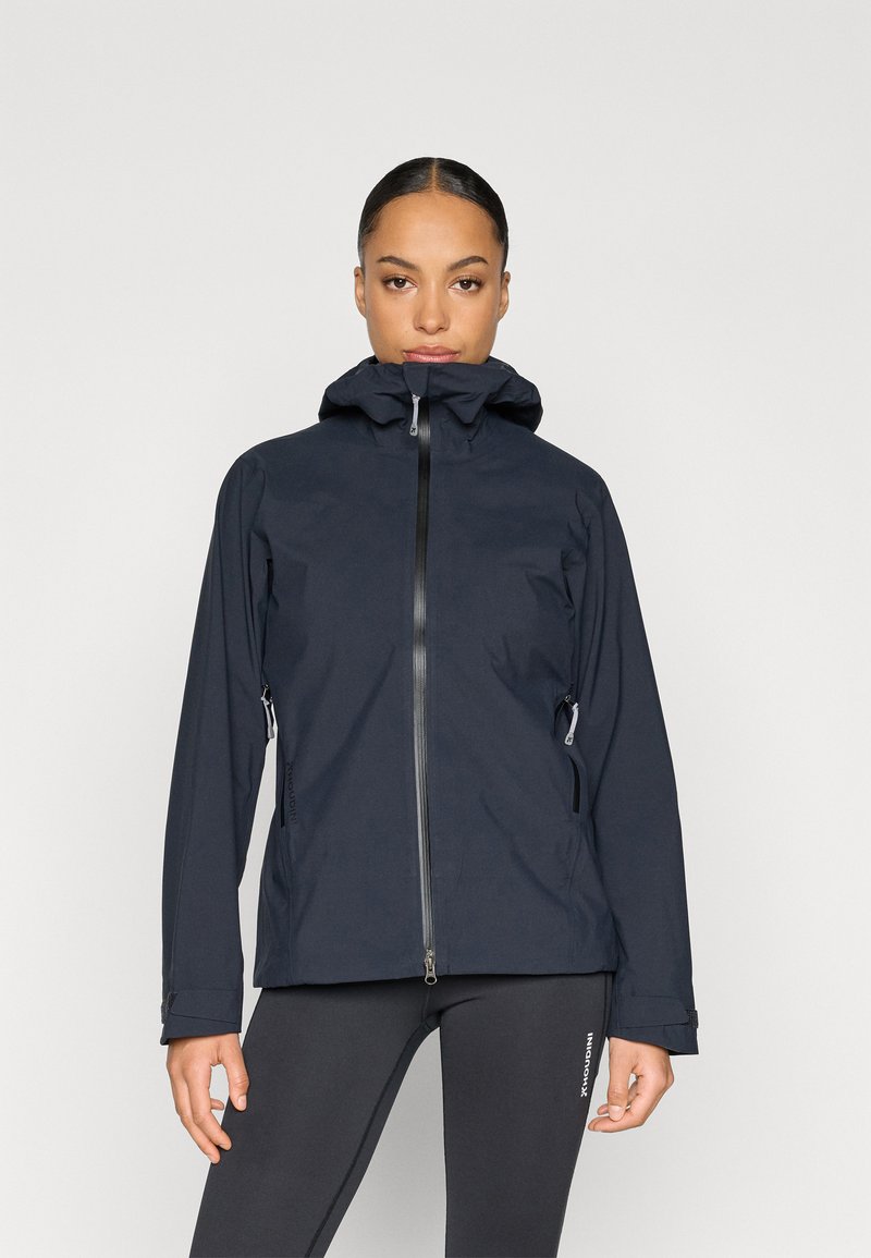 Tmavomodrá nepremokavá bunda s vysokým golierom, predným zipsom a nastaviteľnou kapucňou. Má bočné vrecká a elastické manžety pre pevné uchytenie.