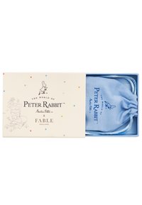 Sininen kangaspussi, jossa on teksti "Peter Rabbit", sijoitettuna kermaiseen laatikkoon, jossa on monivärisiä pisteitä ja kuvastoja hahmosta.